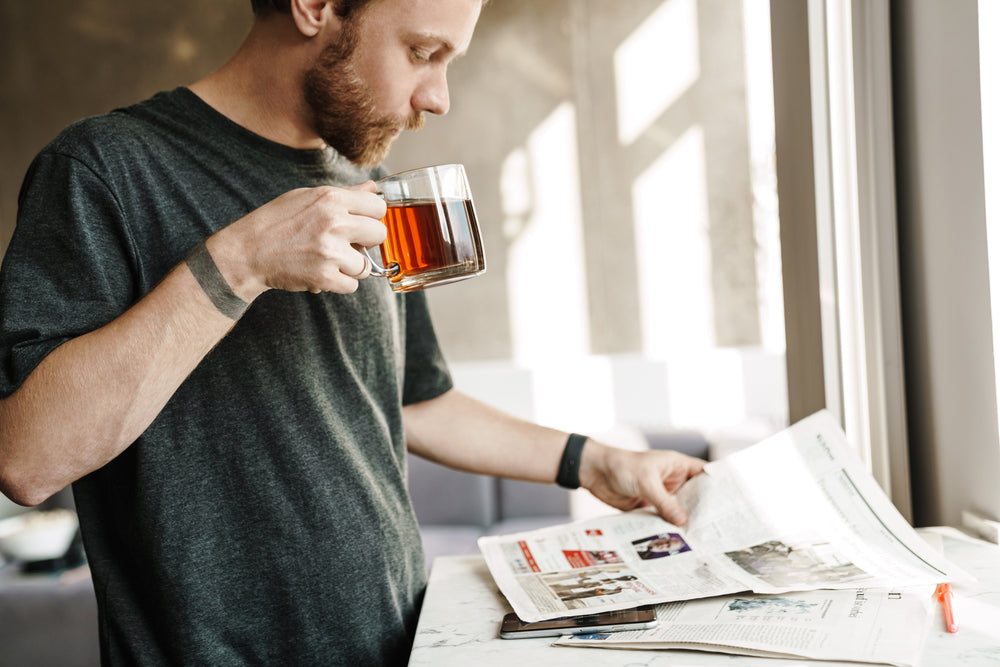 Mann trinkt Tee und liest Zeitung